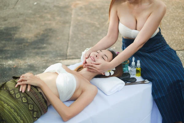 İki Asyalı seksi kadın açık havada spa masajı yapıyor.