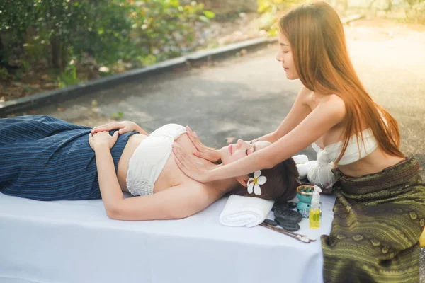 İki Asyalı seksi kadın açık havada spa masajı yapıyor.