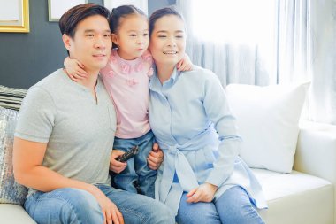 Mutlu Asyalı aile oturma odasındaki kanepede tablet izliyor.