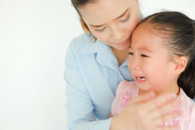 Ağlayan Asyalı küçük kız yalnız bir anne tarafından teselli ediliyor.