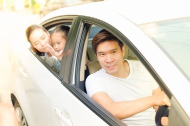Mutlu Asyalı aile arabada oturuyor.