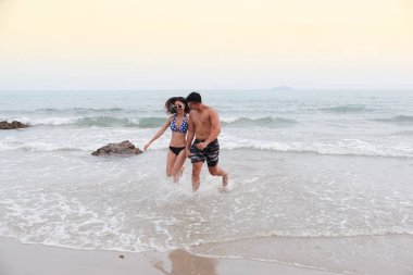 Asyalı aşık bir çift, sahilde seksi bikini, yaz mevsiminde mutlu bir hayat.