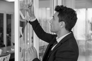 İş adamı toplantı odasındaki camlara not yapıştırıyor.