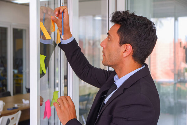 businessman use post it notes on the glass in office meeting room