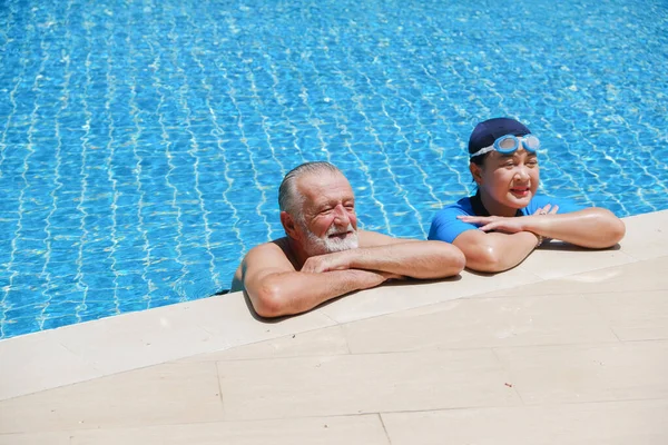 ポートレートアジアのシニア女性とCaucasian古いです男一緒に休息でスイミングプールの端にクラブハウス — ストック写真