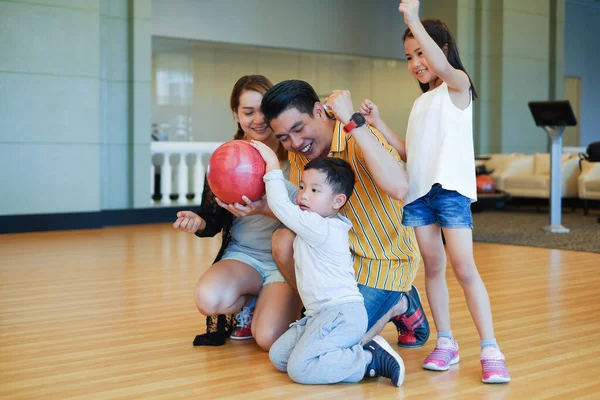 Asyalı aile birlikte bowling oynuyor.