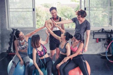 Gülümseyen Asyalı arkadaşlar, mutlu genç kadınlar ve erkekler spor merkezinde çalıştıktan sonra birlikte rahatlıyorlar, spor ve kilo verme konsepti.