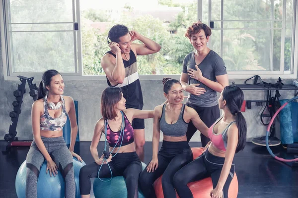 Gülümseyen Asyalı arkadaşlar, mutlu genç kadınlar ve erkekler spor merkezinde çalıştıktan sonra birlikte rahatlıyorlar, spor ve kilo verme konsepti.