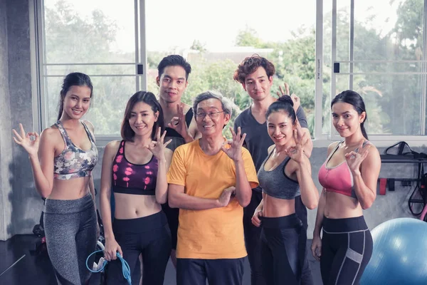 Asyalı son sınıf öğrencisi ve genç grup üyeleri spor salonunda farklı yaşlarda arkadaşlar.