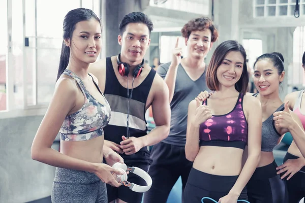 Gülümseyen Asyalı arkadaşlar, mutlu genç kadınlar ve erkekler spor merkezinde çalıştıktan sonra birlikte rahatlıyorlar, spor ve kilo verme konsepti.