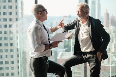 İki kıdemli iş adamı, birlikte çalışmak için gökdelen ya da ofiste buluşuyor.