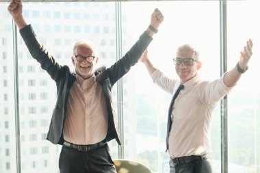 İki kıdemli iş adamı, birlikte çalışmak için gökdelen ya da ofiste buluşuyor.