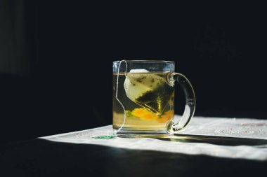 Yeşil çay poşeti güneşin altında bir fincanda