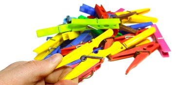 El bir mandal tutuyor, arka planda beyaz bir arka planda izole edilmiş renkli elbise askıları var.