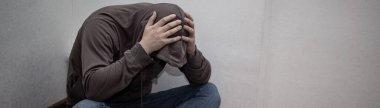 Kapüşonlu ve köşede tek başına oturan umutsuz genç uyuşturucu bağımlısının afişi. Üzüntü, depresyon ve hayat sorunları kavramı