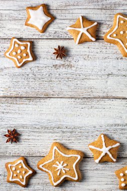 Beyaz ahşap bir arka planda parıltı ve baharat desenleri olan bir yıldız şeklinde Noel zencefilli ekmek sınırı. Kopyalama alanı olan üst görünüm