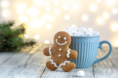 Beyaz ahşap arka planda şekerleme ve zencefilli adam olan mavi bir bardak sıcak içecek. Şenlikli Xmas geçmişi. Bokeh ile geleneksel Noel atmosferi. Yeni yıl tatili konsepti.