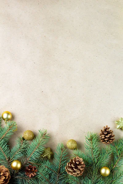 テキストのコピースペースを持つクリスマスカードのクラフト紙の上にコーンと金の装飾とモミの木の枝の境界 新年のコンセプト 休日の背景 クリスマスのモックアップ トップビュー フラットレイアウト — ストック写真