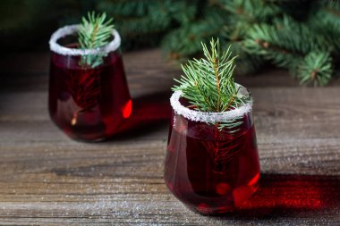 Köknar ağacı dalları böğürtlen ve şekerle süslenmiş kızılcık kırmızı içeceği. Noel sıcak şarabı bardaklarda doğal ahşap arka planda.
