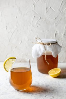 Çiğ mayalanmış ev yapımı alkolik ya da alkolsüz kombu çayı. Buzlu çay ve sağlıklı probiyotik bardakta ve beyaz arka planda limon dilimi.