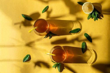 Çiğ mayalanmış ev yapımı alkolik ya da alkolsüz kombu çayı. Buzlu çay ve bardakta doğal probiyotik, limon dilimi ve sarı arka planda nane. Sert gölge