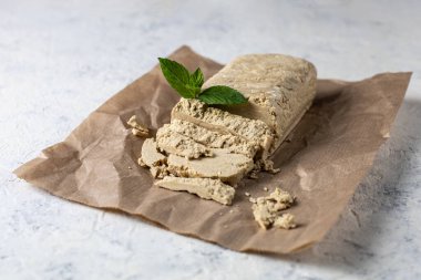 El işi kağıdında kesilen halva. Beyaz arka planda nane yapraklı tatlı.