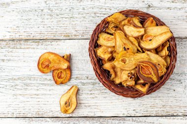 Beyaz ahşap arka planda hasır sepette kurumuş armut dilimleri yığını. Kurutulmuş meyve cipsi. Sağlıklı yiyecekler. Üst görünüm