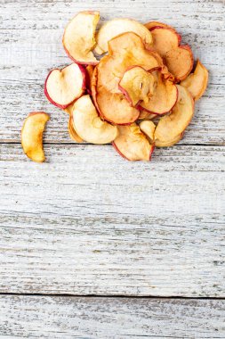 Beyaz ahşap arka planda dilimlenmiş kurumuş elma yığını. Kurutulmuş meyve cipsi. Sağlıklı yiyecekler. Kopyalama alanı olan üst görünüm