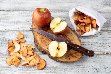 Ahşap zemin üzerinde kurumuş elma ve taze olgun elmalar yığını. Kurutulmuş meyve cipsi. Sağlıklı vejetaryen yemekleri