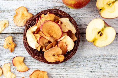 Ahşap zemin üzerinde kurumuş elma ve taze olgun elmalar yığını. Kurutulmuş meyve cipsi. Sağlıklı vejetaryen yemekleri