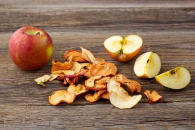 Ahşap zemin üzerinde kurumuş elma ve taze olgun elmalar yığını. Kurutulmuş meyve cipsi. Sağlıklı vejetaryen yemekleri
