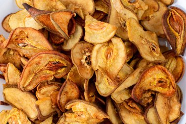 Ahşap arka planda beyaz bir tabakta dilimlenmiş kuru armut yığını. Kurutulmuş meyve cipsi. Sağlıklı yiyecekler. Üst görünüm yakın plan