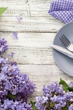 Tabak çatalı ve beyaz ahşap arka planda leylak çiçekleriyle süslenmiş bıçak ile servis masası. 2022 yılının modaya uygun renginde fotokopi alanı olan üst görünüm. 2022 Yılı Rengi.