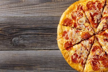 Doğal ahşap arka planda lezzetli ev yapımı pepperoni pizza. Geleneksel salamlı ve peynirli klasik pizza. Metin için kopyalama alanı olan üst görünüm. Düz yatıyordu