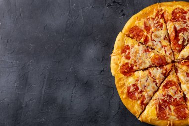 Koyu arka planda ev yapımı lezzetli biberli pizza. Geleneksel salamlı ve peynirli klasik pizza. Metin için kopyalama alanı olan üst görünüm. Düz yatıyordu