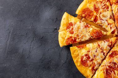 Koyu arka planda ev yapımı lezzetli biberli pizza. Geleneksel salamlı ve peynirli klasik pizza. Metin için kopyalama alanı olan üst görünüm. Düz yatıyordu