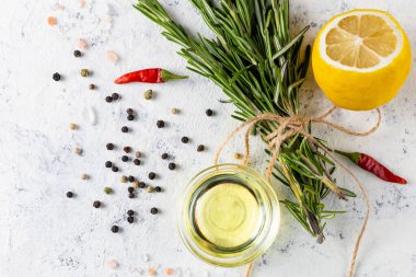 Açık beyaz arka planda biber, tuz, limon ve yağlı bir demet yeşil biberiye. Tarifler için baharat ve bitkiler. Kopyalama alanı olan üst görünüm.