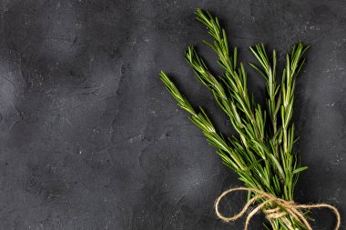 Koyu siyah arka planda bir demet yeşil biberiye. Tarifler için baharat ve bitkiler. Kopyalama alanı olan üst görünüm.