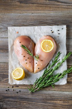 Biberiyeli kalp şeklinde çiğ tavuk filetosu ve doğal ahşap arka planda baharatlar. Üst görünüm