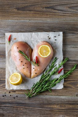 Biberiyeli kalp şeklinde çiğ tavuk filetosu ve doğal ahşap arka planda baharatlar. Üst görünüm