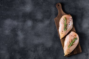 Koyu arkaplanda biberiyeli taze tavuk filetosu ve baharat. Yemek geçmişi, yemek malzemeleri. Kopyalama alanı olan üst görünüm