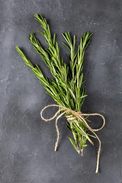 Koyu siyah arka planda bir demet yeşil biberiye. Tarifler için baharat ve bitkiler. Kopyalama alanı olan üst görünüm.