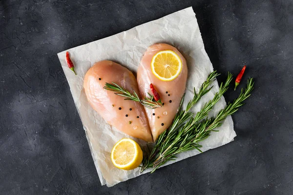 Biberiyeli kalp şeklinde çiğ tavuk filetosu ve koyu beton arka planda baharatlar. Kopyalama alanı olan üst görünüm