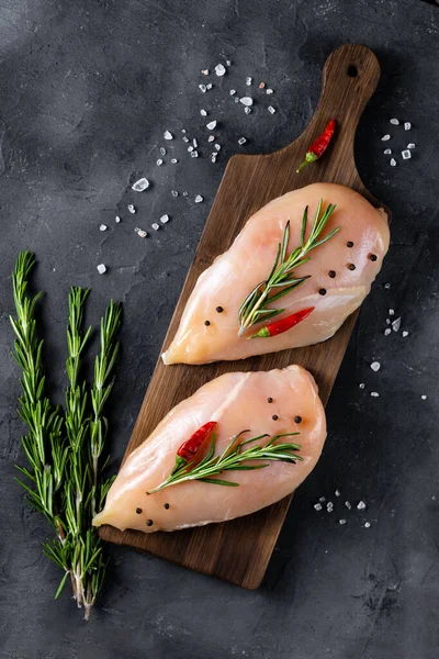 Koyu arkaplanda biberiyeli taze tavuk filetosu ve baharat. Yemek geçmişi, yemek malzemeleri. Üst görünüm