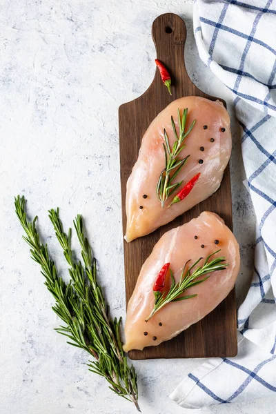 Biberiyeli çiğ tavuk filetosu ve beyaz ışıklı arka planda baharatlar. Yemek geçmişi, yemek malzemeleri. Üst görünüm