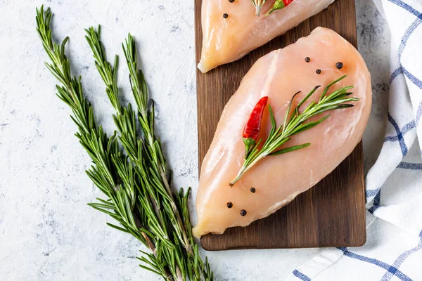 Biberiyeli çiğ tavuk filetosu ve beyaz ışıklı arka planda baharatlar. Yemek geçmişi, yemek malzemeleri. Üst görünüm