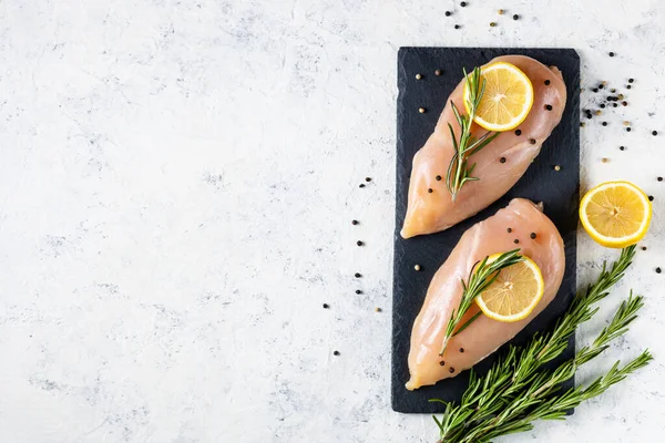 Beyaz arka planda biberiye, limon ve baharatlı çiğ tavuk filetosu. Yemek geçmişi, yemek malzemeleri. Kopyalama alanı olan üst görünüm