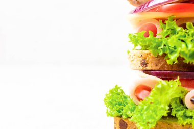 Jambonlu, peynirli, domatesli, soğanlı sandviç. Beyaz zemin üzerinde tam tahıllı ekmek ve kopyalama alanı olan çok katmanlı sandviç.