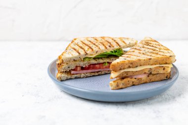 Jambonlu, peynirli, domatesli, soğanlı sandviç. Beyaz arka planda tahıl ekmeği olan klasik kulüp sandviçi..