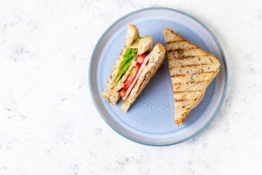 Jambonlu, peynirli, domatesli, soğanlı sandviç. Klasik kulüp sandviçi. Beyaz arka planda tahıllı ekmek ve fotokopi alanı var.